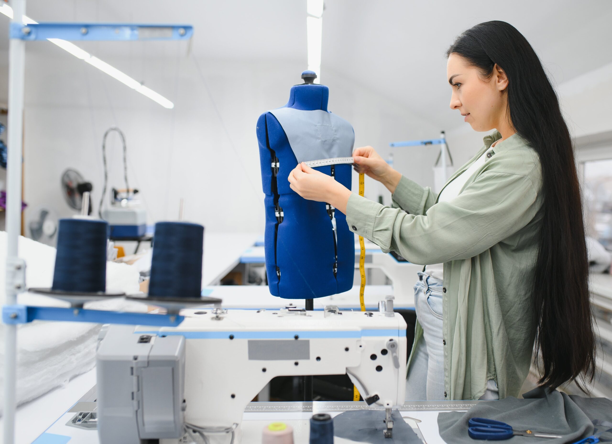 happy-female-dressmaker-working-with-sewing-machine-textile-factory-min